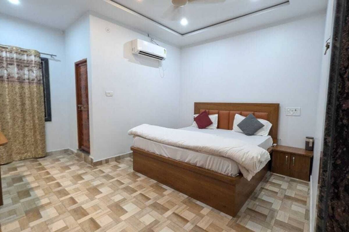 Un dormitorio con cama de madera, mesita de noche, equipo de aire acondicionado y piso con diseño.