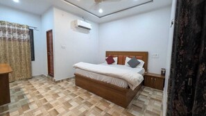 Un dormitorio con cama de madera, mesita de noche, equipo de aire acondicionado y piso con diseño.