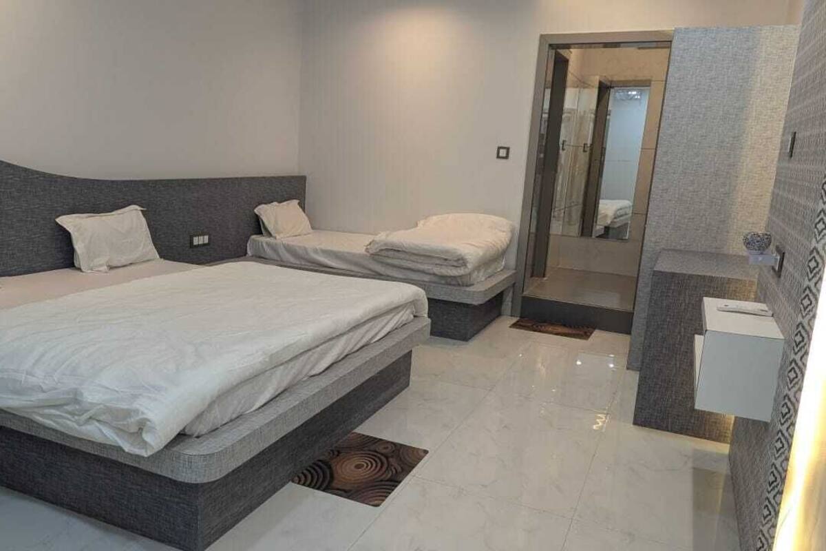 Un dormitorio moderno con dos camas, zona de ducha y baño.