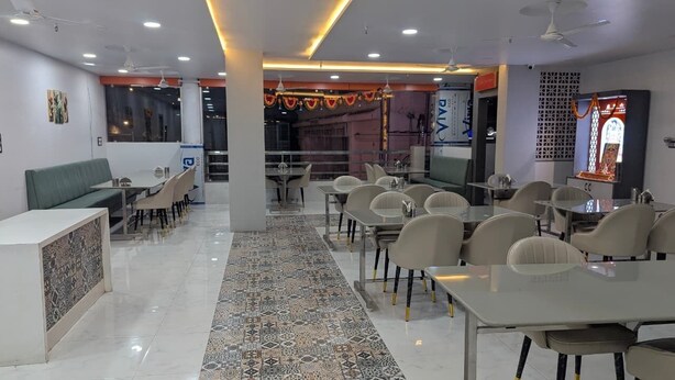 Un restaurante moderno con varias mesas y sillas, una alfombra estampada y una zona de recepción.