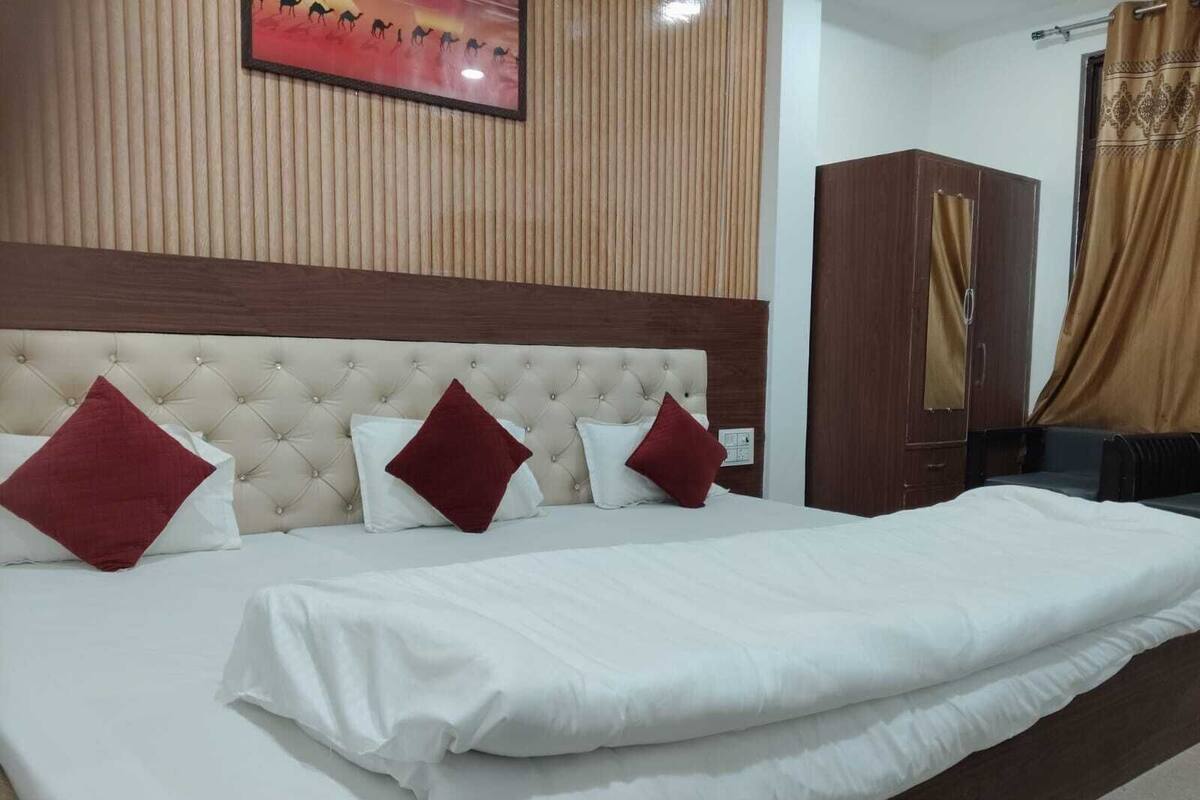 Habitación de hotel con una cama grande, cabecera, armario y un cuadro en la pared.