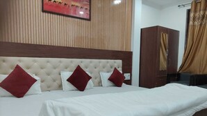 Habitación de hotel con una cama grande, cabecera, armario y un cuadro en la pared.