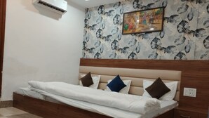 Una cama individual con cabecera de madera, un aire acondicionado de pared y un papel tapiz estampado con un cuadro enmarcado encima.