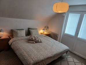 A bedroom with a bed, bedside lamps, a fan, and a window with blinds. - Cosy HAPPY PLACE Experience the kingdom of Crystal in the Swedish Smaland. (Boda glasbruk)
