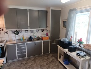 Une cuisine avec des meubles de couleur grise, un pare-feu en carrelage, un évier et une fenêtre avec des rideaux.