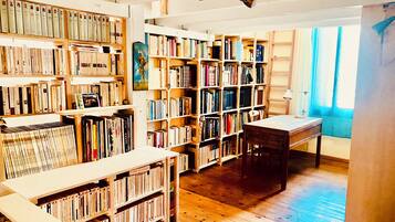 Een kamer met houten boekenplanken vol boeken, een houten bureau en een rood tapijt.