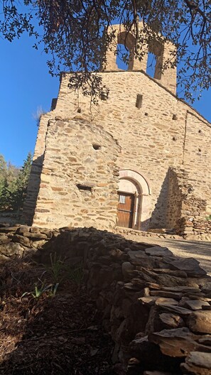 A stone building with a wooden door and a bell tower. - The Cocon Lou Jaïa (Corbère)