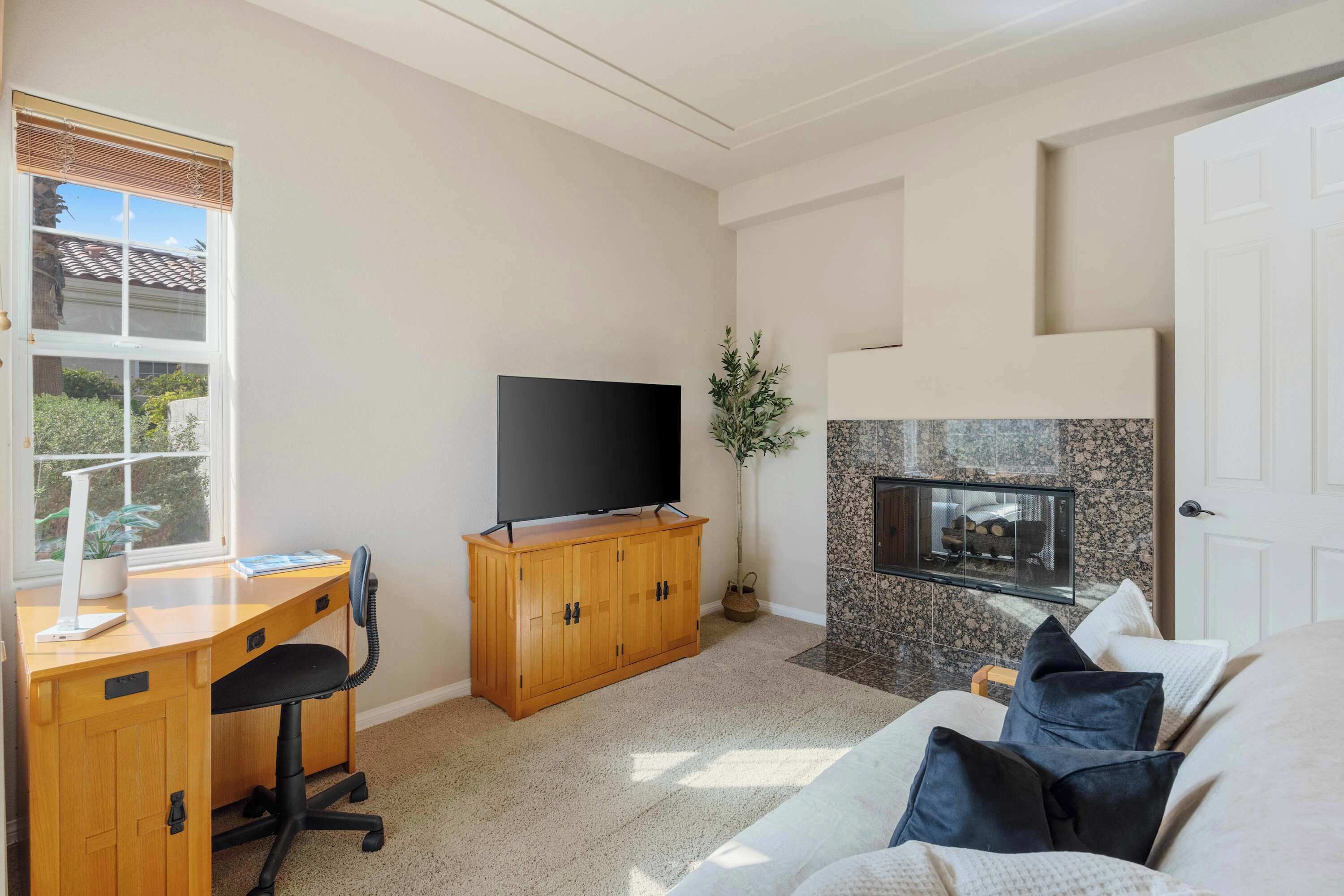 Un salon avec un bureau en bois, une télévision, une cheminée et un canapé.