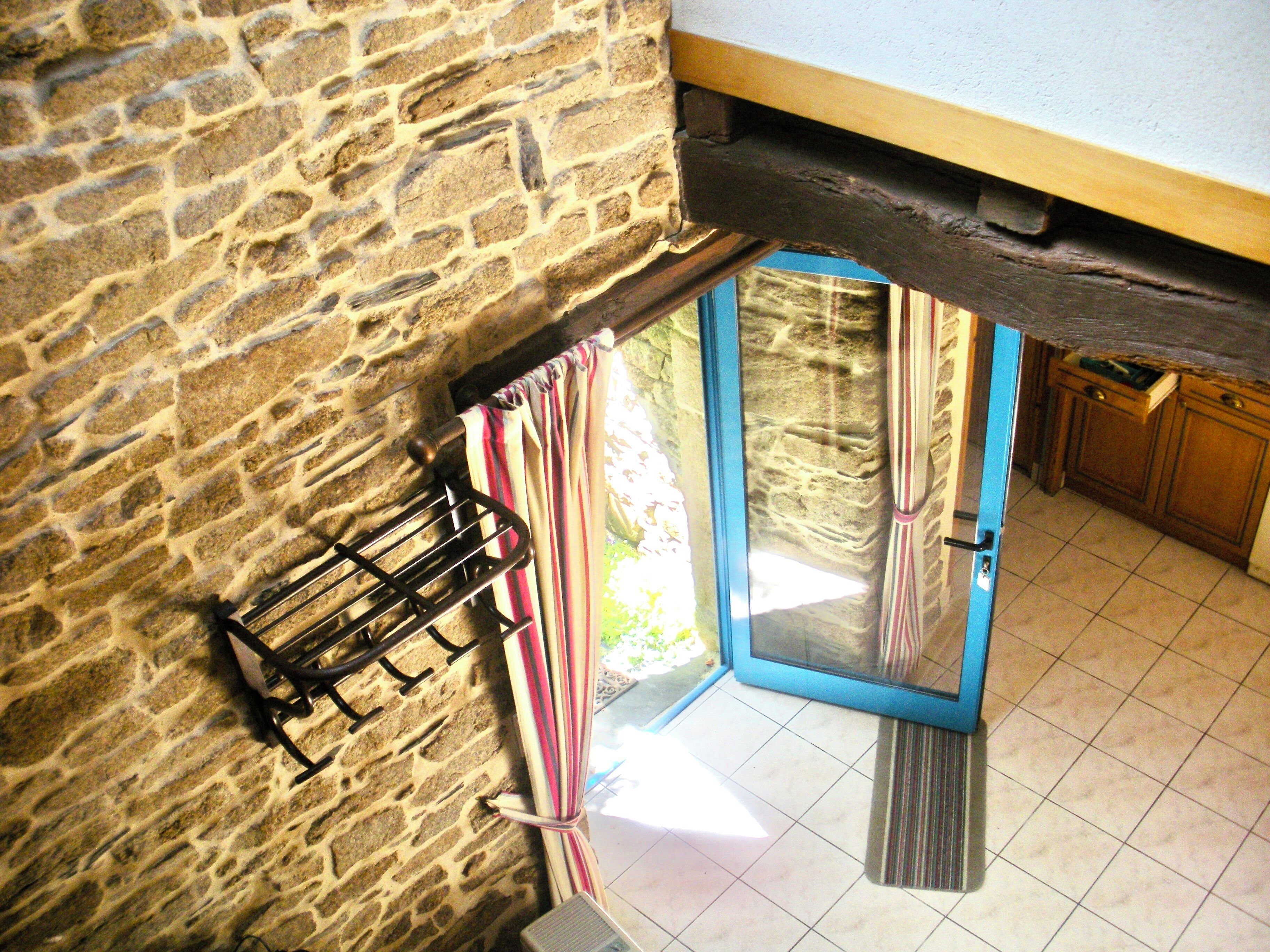 A stone wall, a rack with items, a blue door, and a kitchen area.