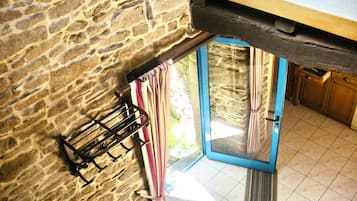 A stone wall, a rack with items, a blue door, and a kitchen area.