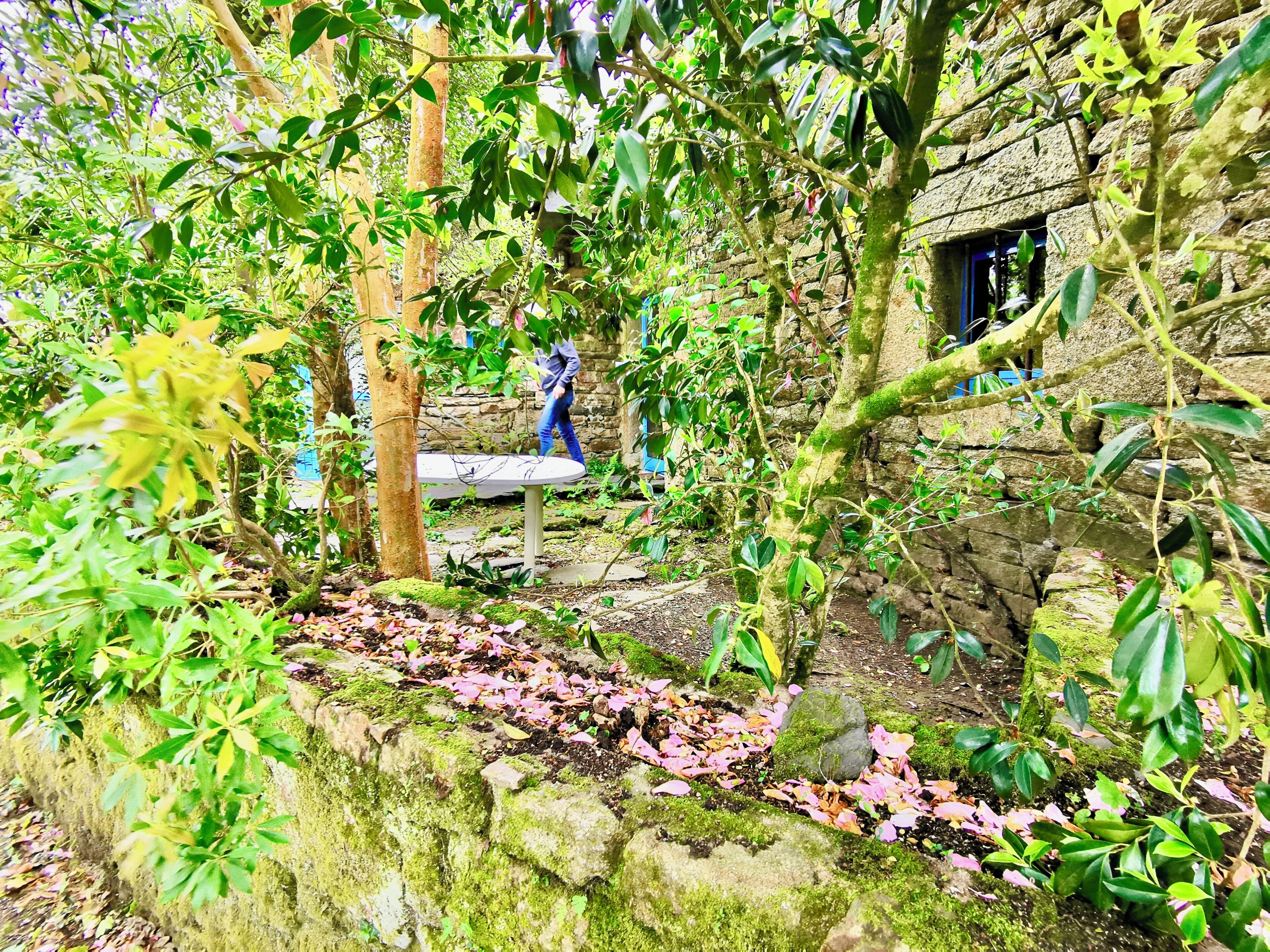 Un edificio de piedra con un jardín rústico, un banco y una estatua.