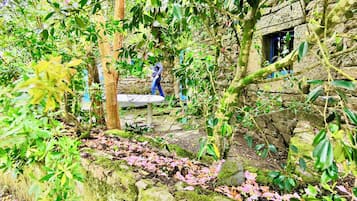 Un edificio de piedra con un jardín rústico, un banco y una estatua.