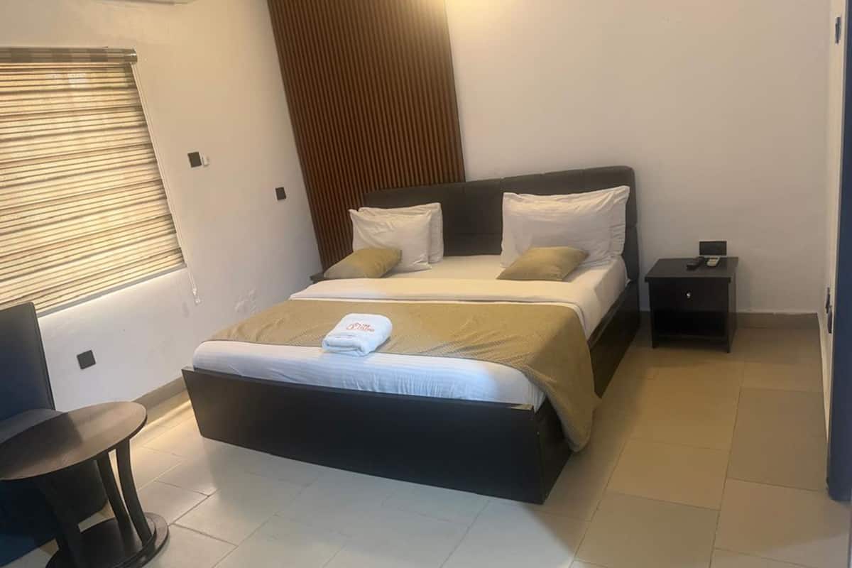 A hotel room with a bed, bedside table, and a chair.