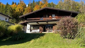 Eine zweistöckige Chalet mit Balkon, umgeben von einem gepflegten Garten und Herbstlaub.