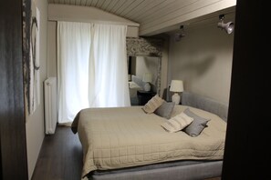 A bedroom with a bed, a nightstand, a lamp, a mirror, and a window with curtains. - Chalet to feel good Golf, ski, mountains, lake (Goldegg)