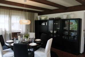 A dining area with a round table set for four, surrounded by chairs. A cabinet with glass doors is to the right, displaying various dishes and glassware. - Chalet to feel good Golf, ski, mountains, lake (Goldegg)