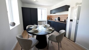 A modern kitchen with dark cabinetry, a central island, and a dining area with a round table and four chairs. - Liboria vacation apartment Starnberg with balcony for 6 persons (Starnberg)