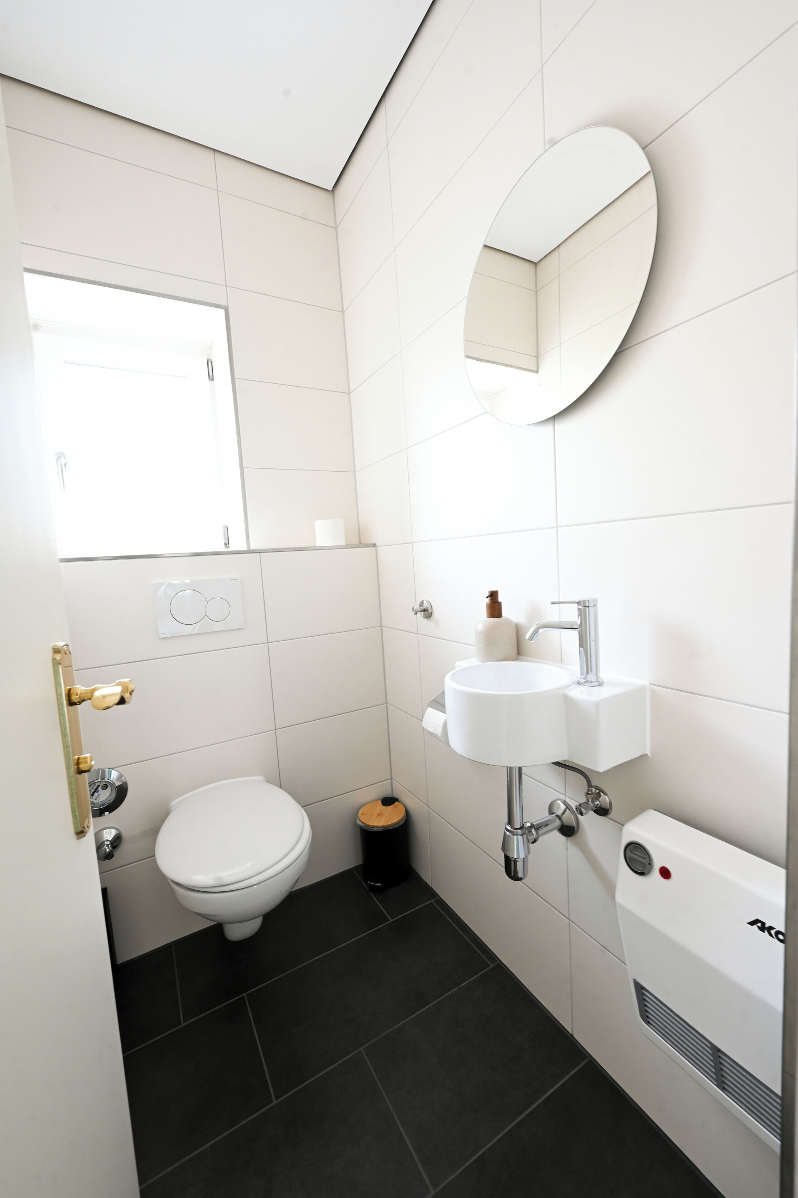 Une petite salle de bain moderne, équipée de toilettes, d’un lavabo et d’un miroir.