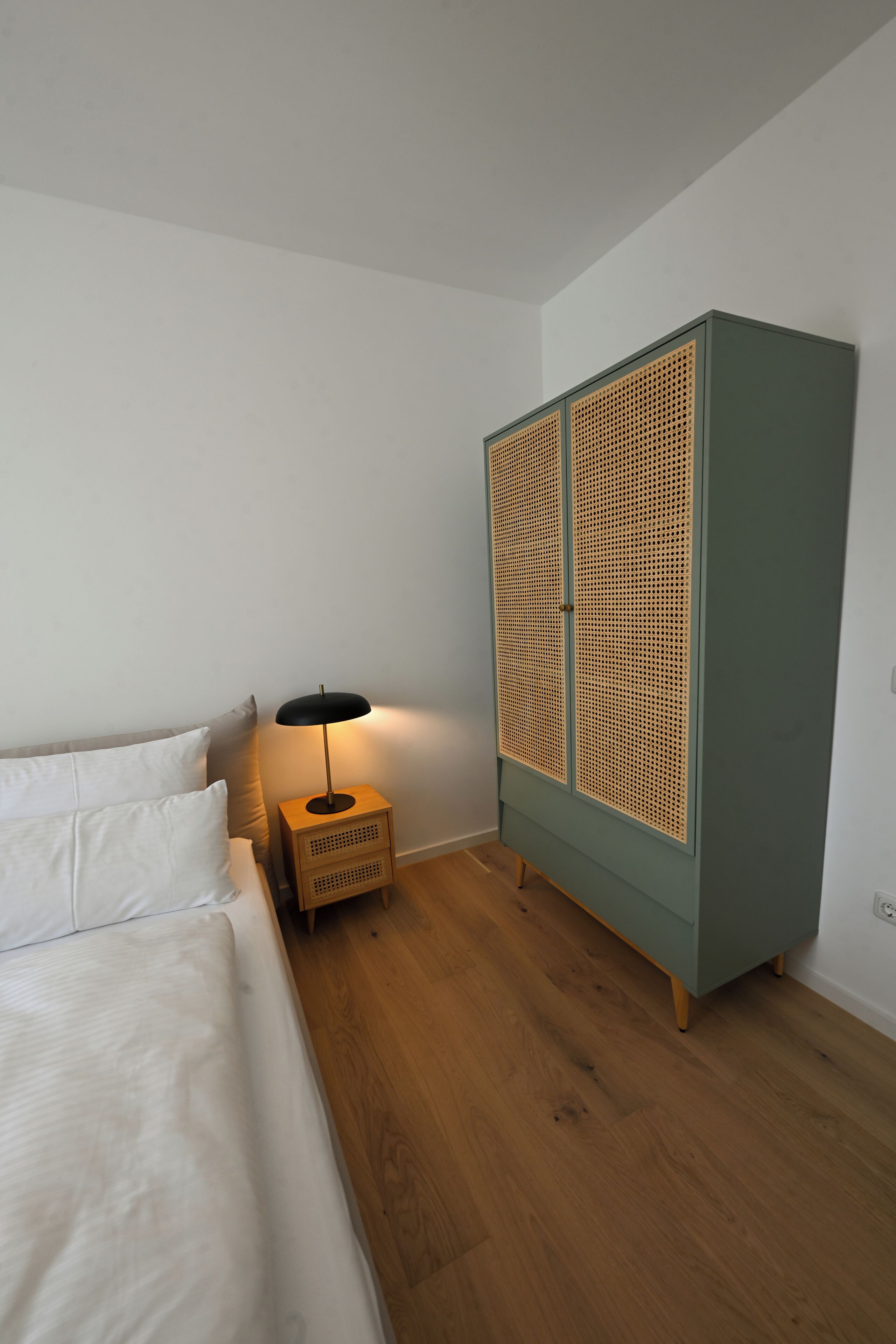 Ein Schlafzimmer mit einem Bett, einem Nachttisch mit Lampe und einem Kleiderschrank.