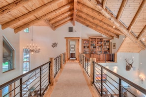 Ein Holzinnenraum mit hoher Decke, einer zentralen Treppe, Bücherregalen und einem aufgehängten Hirschkopf.