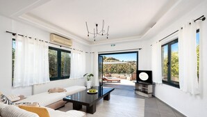 Ein modernes Wohnzimmer mit einer Couch, einem Couchtisch und Blick ins Freie.