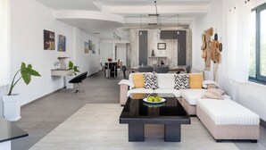 Ein modernes Wohnzimmer mit einer Couch, einem Couchtisch mit Äpfeln, einem Essbereich und einer Küche im Hintergrund.
