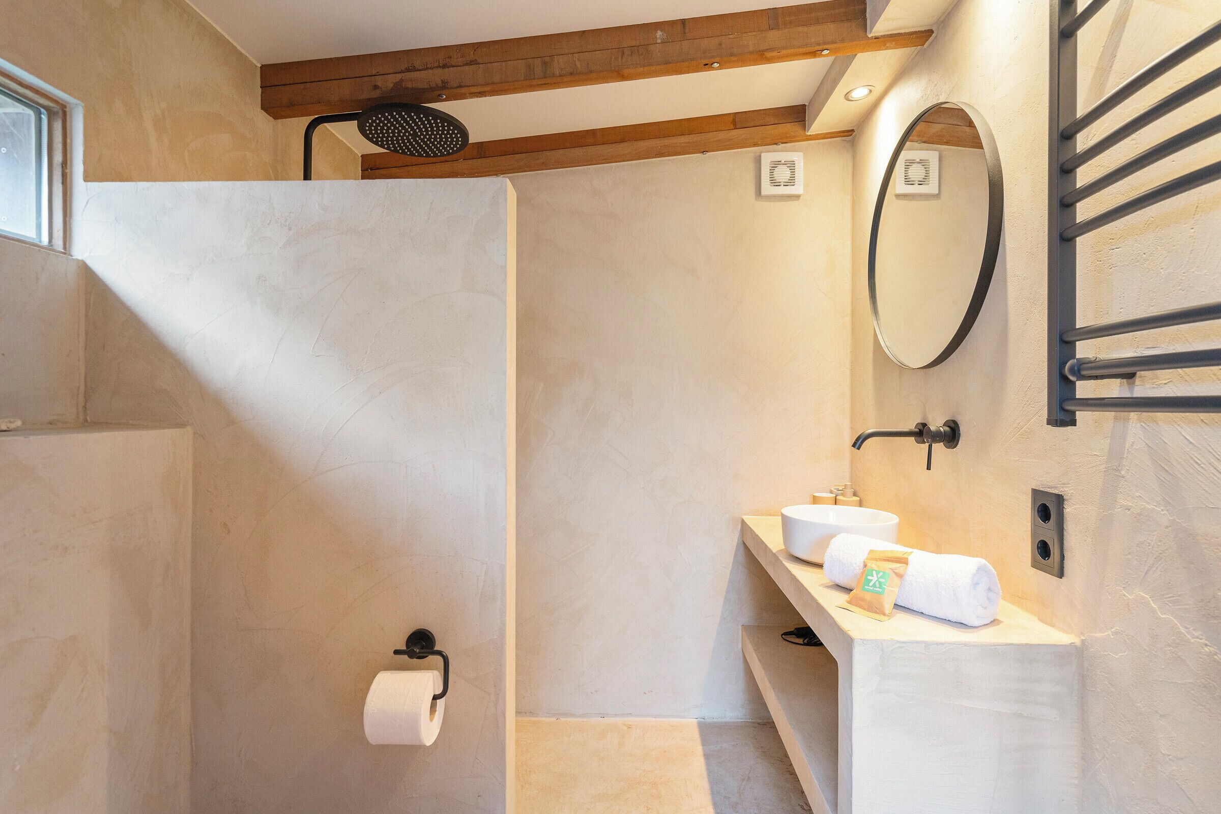 A modern bathroom with a shower, a sink with a towel, and a mirror.