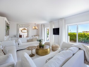 Ein modernes Wohnzimmer mit einem weißen Sofa, einem runden Couchtisch und einem an der Wand montierten Fernseher.