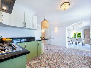 A modern kitchen with green cabinets, a gas stove, and a fruit bowl.