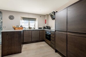 Eine moderne Küche mit dunklen Holzschränken, einem eingebauten Backofen und einem Fenster mit Blick.