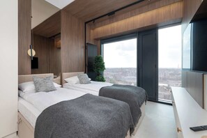 A modern hotel room with two beds, a large window with a city view, and a minimalist design. - Luxury Apartment with Air Conditioning | 25th Floor (Katowice)