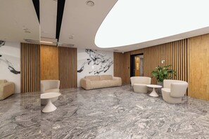 A modern lobby with a marble floor, sofas, a coffee table, and a plant. - Luxury Apartment with Air Conditioning | 25th Floor (Katowice)
