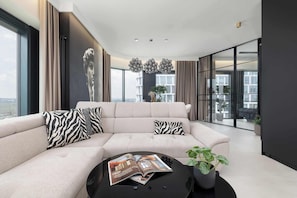 Ein modernes Wohnzimmer mit einer großen Couch, einem Couchtisch mit einer Zeitschrift und einer Topfpflanze.