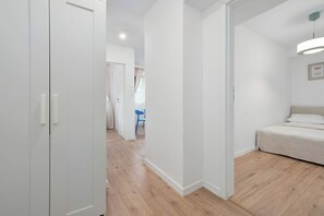A bedroom with a bed, a wardrobe, and a door leading to another room. - Bright Apartment in the City Centre | Family City Break (Łódź)