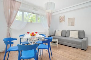 A room with a dining table, blue chairs, a grey sofa, and a small side table.