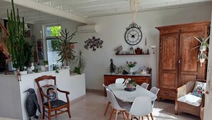 A dining area with a white table and chairs, a wooden cabinet, and various plants.