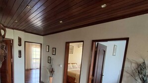 Un pasillo amplio con piso de granito pulido, techo de paneles de madera y varias puertas que dan a diferentes habitaciones.