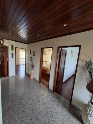 A spacious hallway with a polished granite floor, wooden panel ceiling, and multiple doors leading to different rooms. - Constança House 10 min. from Fonte da Telha (Corroios)