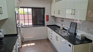 Cocina moderna con armarios blancos, encimera negra, lavavajillas integrado y ventana con vistas al exterior.