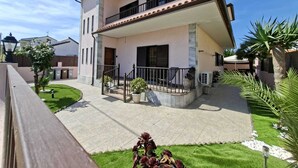 Una casa de dos pisos con balcón, un pequeño jardín y un camino de entrada pavimentado.