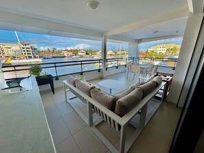 A balcony with a sofa, a dining table, and chairs. - The Marina Suites (Saint francois)