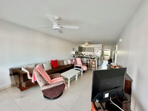 A living room with a sofa, chairs, a TV, and a ceiling fan. - The two suites at the Marina (Saint francois)