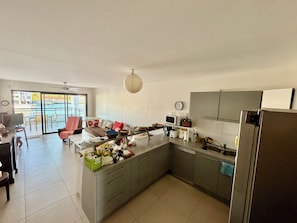A modern kitchen with a central island, grey cabinets, a microwave, and a refrigerator. - The two suites at the Marina (Saint francois)