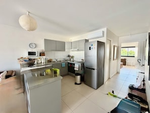 A modern kitchen with grey cabinets, a stainless steel refrigerator, and a microwave. - The two suites at the Marina (Saint francois)
