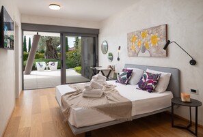A modern bedroom with a bed, a bedside table, a painting, and a view of the outdoors. - Luxury Villa Old Olive I - heated private pool, jacuzzi, sauna and more, for 12 persons. (Vodnjan)