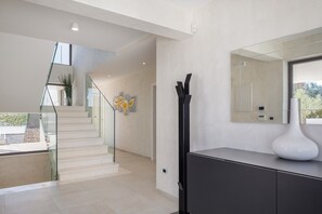 A modern interior with a staircase leading to an upper level, a large mirror, and a minimalist console table. - Luxury Villa Old Olive I - heated private pool, jacuzzi, sauna and more, for 12 persons. (Vodnjan)