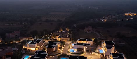 A residential area with modern houses, a swimming pool, and a view of the landscape.
