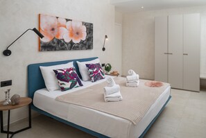 Une chambre à coucher moderne avec un lit, des oreillers, un tableau, une table de chevet et une armoire.