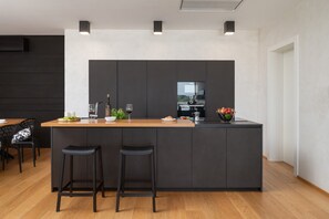 A modern kitchen with a central island, bar stools, and a dining area with a table and chairs. - Luxury Villa Old Olive I - heated private pool, jacuzzi, sauna and more, for 12 persons. (Vodnjan)