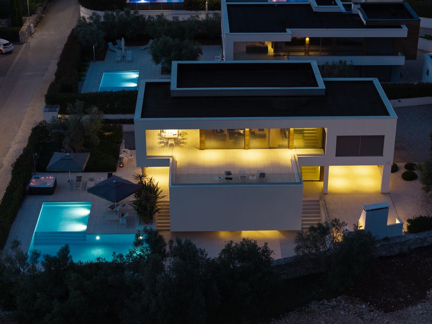 Une maison moderne à deux étages, dotée d’une piscine, d’un espace extérieur aménagé et d’un intérieur bien éclairé.